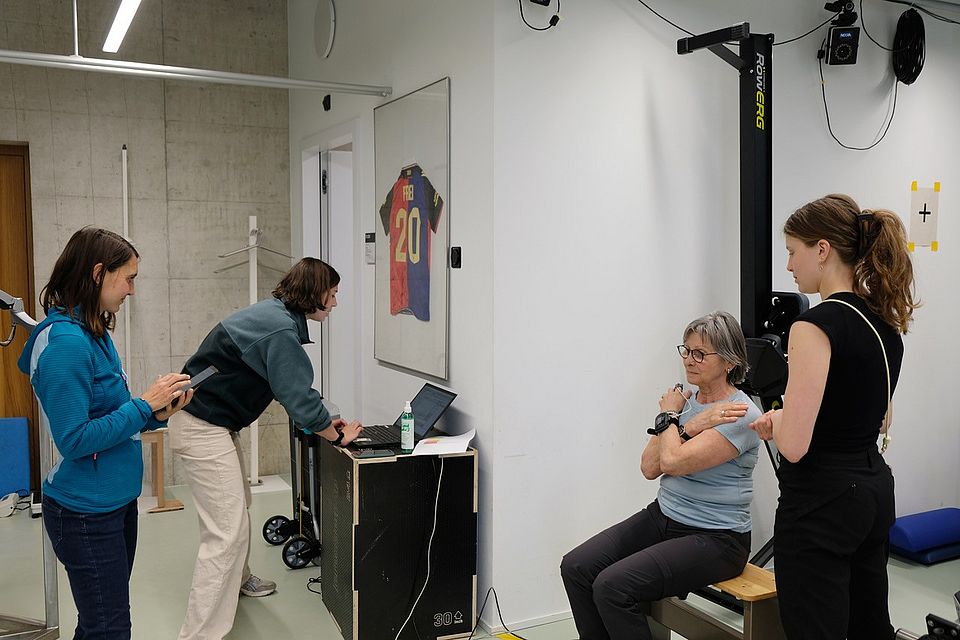 Unsere Probandin beim Sit-to-Stand Test, zusammen mit dem INCLUDE Team Larissa Hänsli, Noemie Marti, und Sierra Arn. 